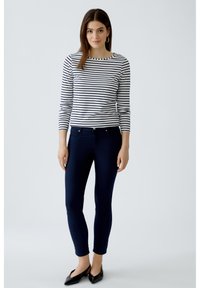 Gestreiftes Langarmshirt mit marineblauen Jeans, runder Ausschnitt und Slim-Fit. Schwarze Ballerinas betonen das Ensemble.