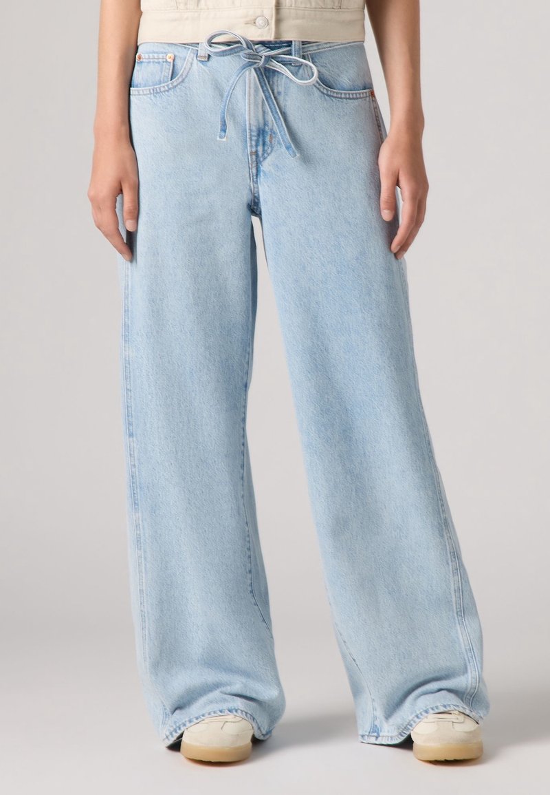 Ljusblå denimbyxor med vida ben och dragsko i midjan, med en blekt finish, sidofickor och uppvikt nederkant. Slät textur.