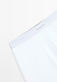 Pantaloni boxer in cotone bianco con una morbida vita elastica etichettata "Massimo Dutti." Presentano una superficie liscia e un design minimale.