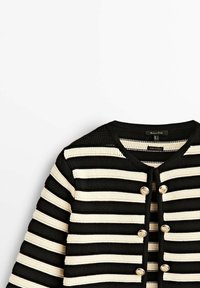 Cardigan en maille rayé noir et blanc avec col rond et six boutons dorés sur le devant, présenté sur un fond blanc.
