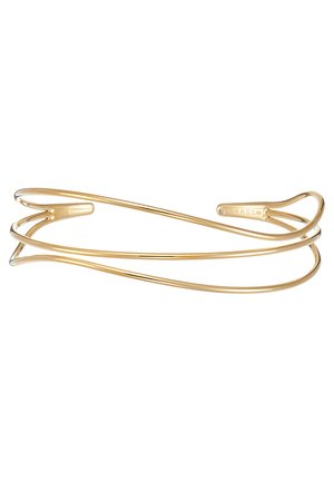 Bracelet en métal doré avec un design ouvert, présentant des bords lisses et arrondis ainsi qu'une forme fluide. Fini poli.