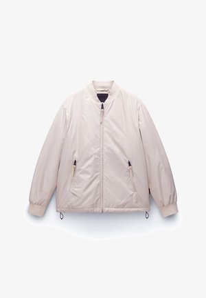 Light beige bomber jacket with a front zipper, elastic cuffs, and two zippered side pockets. Smooth, water-resistant fabric.