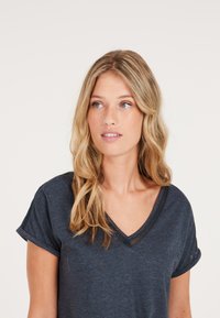 T-shirt blu scuro a V in tessuto morbido, con maniche corte con orli arrotolati e dettaglio in rete sullo scollo.