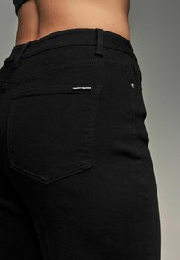 Zwarte denim broek met een slim fit ontwerp, textuurstof, een achterzak met een zilveren accent en een middel hoge taille.