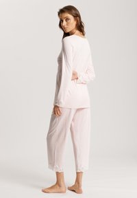Helles rosa Loungewear-Set mit langen Ärmeln, Spitzenbesatz an den Bündchen und Hosenumschlägen, lockerer Schnitt, weicher Stoff und cropped Hosenlänge.