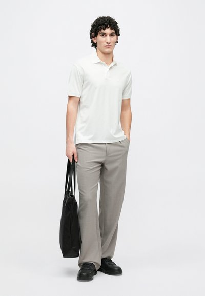 Bílé polo tričko s krátkými rukávy, světle šedé kalhoty, černé tenisky a černá taška přes rameno. Jednoduchý design a měkké textury látek.