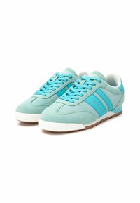 Zapatillas de ante azul claro con suelas de goma blanca contrastantes, con cordones y rayas azules en los laterales. Diseño atlético clásico.