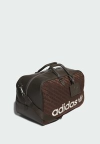 Brown duffel bag with leather trim, fabric body featuring a repeated logo pattern, and a detachable shoulder strap. Zipper closure with tag.