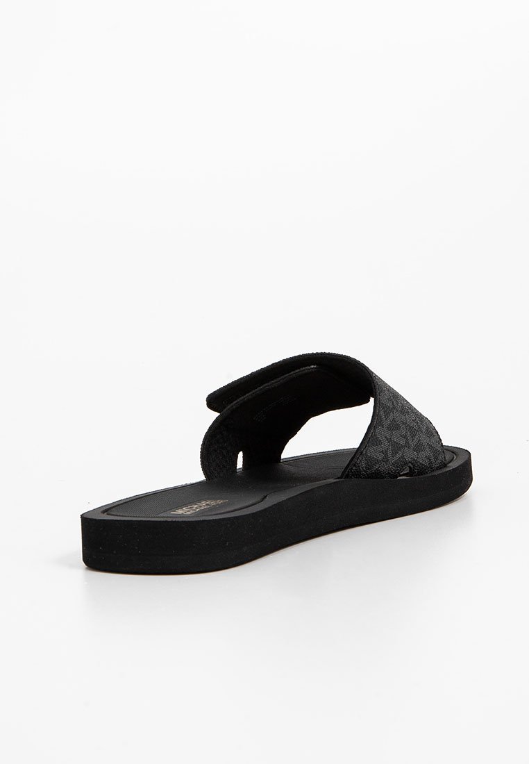 Infradito neri con una fascia superiore texture e una suola piatta e imbottita. La fascia presenta un motivo delicato; il design complessivo è minimalista.