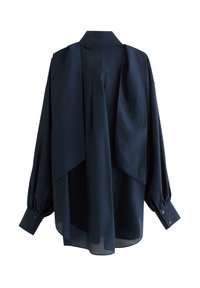 Mørkeblå oversized bluse med krave, lange puffede ærmer og draperet rygdetalje. Fremstillet af letvægtsstof med knaplukning ved ærmerne.