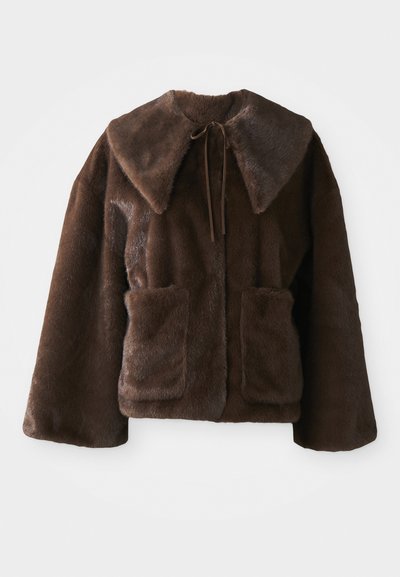 Brūns mākslīgās kažokādas mētelis ar plašu apkakli, priekšējo saišu aizdari, garām piedurknēm un divām priekšējām kabatām uz balta fona.