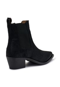 Botas negras hasta el tobillo hechas de material texturizado con paneles laterales elásticos, punta afilada y un tacón bajo apilado.