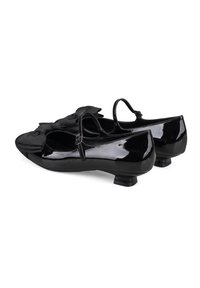Bailarinas de charol negro con detalle de lazo en la puntera, pequeño tacón y tirante en el tobillo para mayor soporte. Textura suave en toda su superficie.