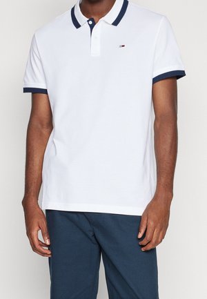 Polo blanc avec col et accents de manches bleu marine. Comprend une patte de boutonnage à trois boutons et un logo brodé sur la poitrine. Manches courtes.