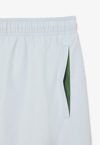 Lichtblauwe shorts met een elastische tailleband, met een groene binnenzak en een gladde stofstructuur.