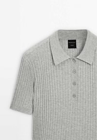 Polo à manches courtes côtelé gris clair avec quatre boutons et un col, étiqueté Massimo Dutti Studio.