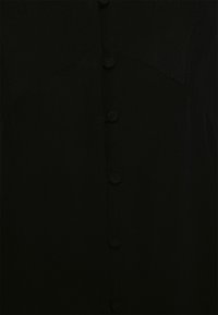 Musta kangas, jossa on pystysuora rivi kuutta kangaspäällysteistä nappia ja näkyvää ompelusviimeistelyä vaatteessa.