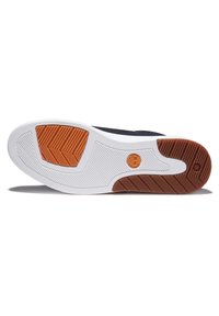 Semelle de basket noire avec une intersemelle blanche et des accents en caoutchouc brun et orange, présentant un motif en chevrons pour l'adhérence.