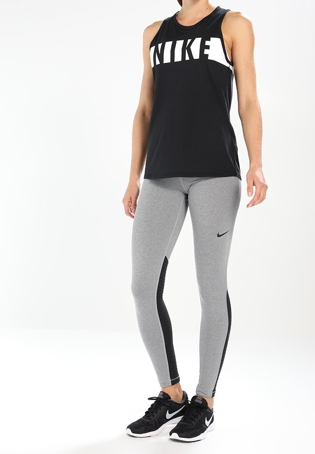 Top sin mangas negro de Nike con un gran logo blanco; leggings grises con paneles laterales negros; zapatillas deportivas negras.