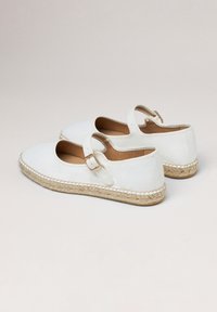 Chaussures espadrilles blanches avec un bout rond, une bride de cheville et une semelle en jute. Matériau en cuir lisse et détails cousus autour de la semelle.