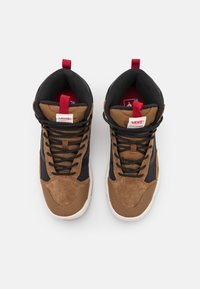 Bruna och svarta högskoor. Ovandelen i mocka och mesh, kontrasterande snören, vadderad krage och en vit gummisula. Röda etiketter på toppen.