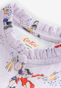 Violeta tekstilija ar volānu apkakli, uz kuras attēloti мультзīmu varoņi supervaroņu tēlā. Ir auduma tagiņš un rozā pogas detaļa.