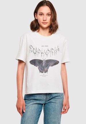 T-shirt en coton blanc avec un grand graphisme d'un papillon noir et un texte stylisé au-dessus. Manches courtes et coupe décontractée.