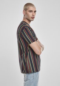 T-shirt rayé bleu marine, aux rayures verticales rouges et jaunes. En coton doux, à manches courtes et coupe décontractée.