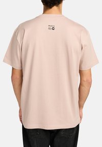 Light pink cotton t-shirt with short sleeves and a crew neckline. Features a small black logo near the collar on the back.