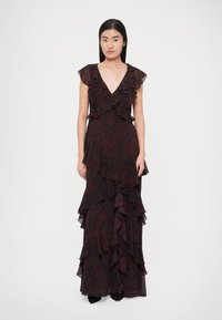 Fekete ruha paisley mintával, réteges fodrokkal, mély V-nyakkivágással, rövid ujjal és légies sziluettel.