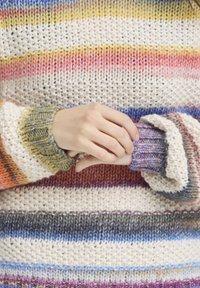 Pull en tricot avec des rayures horizontales aux couleurs comme le rose, le bleu et l'orange, avec un fil texturé et des poignets côtelés affichant une épaisseur variée.