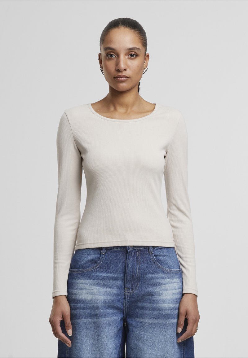 Kermavaate pitkät hihat, pyöreä pääntie, valmistettu ribbymateriaalista, yhdistetty vaaleansinisiin leveälahkeisiin farkkuihin, joissa on sävyeroa.