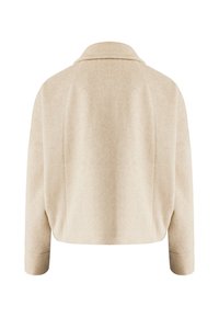 Krémová zkrácená bunda vyrobená z měkké látky; má klasický límec, spadlá ramena a dlouhé rukávy s detaily na manžetách.
