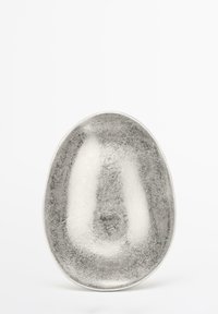 Oval metallskål med en glansig silverfinish. Har en slät insida och en texturerad utsida, vilket skapar en slående kontrast i utseendet.