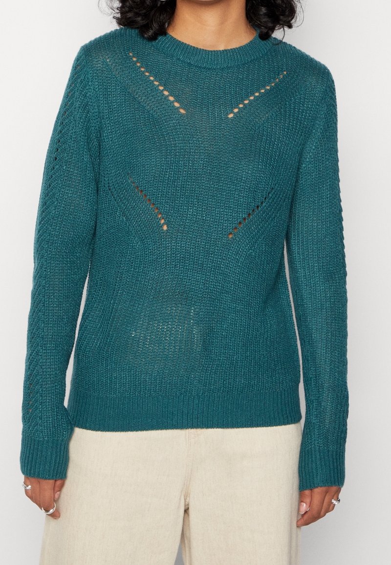 Teal sweter dzianinowy z fakturowanym wzorem, z detalami w formie wycięć oraz ribbowanymi mankietami i dołem. Długie rękawy i okrągły dekolt.