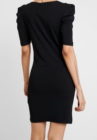 Černé bavlněné šaty s krátkými rukávy se shirring detaily a přiléhavým střihem, končící těsně nad kolenem.