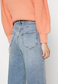 ONLY Petite ONLINC HOPEEX HI WIDE LEG REAPET - Calças de ganga de corte relaxado - light blue denim