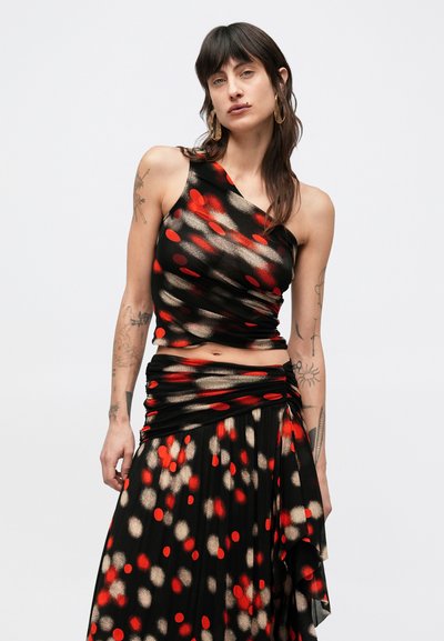 Σετ με crop top ενός ώμου και φούστα με στρώσεις σε μαύρο χρώμα με κόκκινες και χρυσές κυκλικές λεπτομέρειες. Απαλό, ρέον ύφασμα με πιετέ λεπτομέρειες.