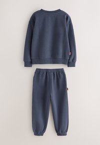 Sudadera azul marino y pantalones deportivos a juego con puños y cintura elásticos, exhibidos planos sobre un fondo neutro.