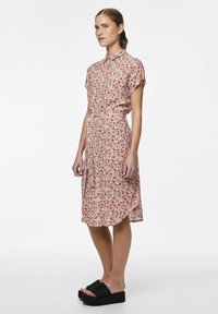 Vestito floreale con maniche corte, colletto e vita cinturata. Motivo colorato di piccoli fiori rossi e rosa su uno sfondo chiaro.