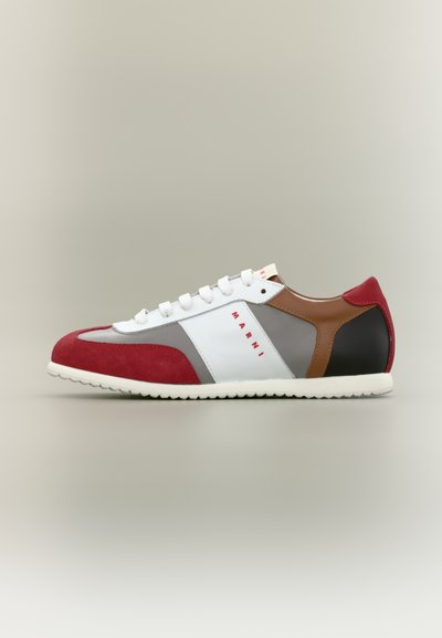 Baskets en suède rouge et cuir blanc avec des accents gris et bruns, dotées d'une semelle en caoutchouc et de lacets blancs. Détail remarquable du logo rouge.