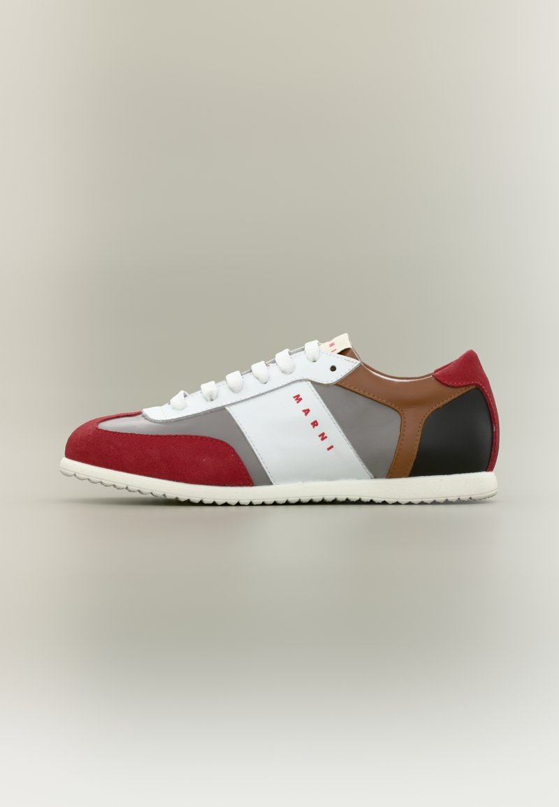 Baskets en suède rouge et cuir blanc avec des accents gris et bruns, dotées d'une semelle en caoutchouc et de lacets blancs. Détail remarquable du logo rouge.