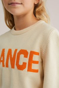 Krämfärgad stickad tröja med orange "DANCE"-text. Har en ribbad rund halsringning och mjukt, texturerat tyg. Tight passform.