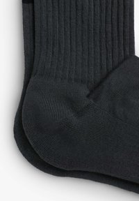 Chaussettes côtelées gris foncé avec une texture lisse. Comprend des zones de talon et d'orteil renforcées, offrant une durabilité et un confort supplémentaires.