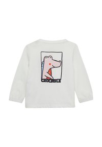 Witte lange mouw shirt met een cartoon krokodil graphic met rode accenten en het woord "CROCODILE" gecentreerd onder de afbeelding.