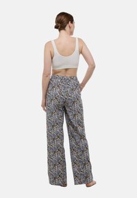 Pantalons larges en coton brossé avec un motif floral bleu, marron et ivoire. Associés à un simple débardeur ivoire.