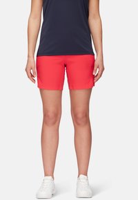 Pantalones cortos deportivos rojos con un patrón texturizado, diseño ajustado y una cintura ligeramente elástica. Combinados con una camiseta azul marino oscura y zapatillas blancas.
