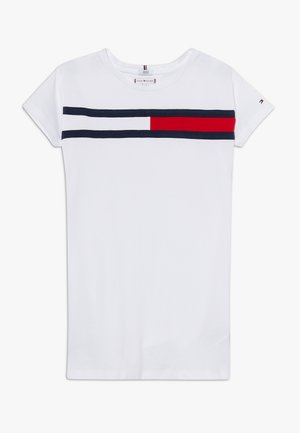 Chemise blanche à manches courtes avec deux rayures horizontales bleu marine et un bloc rouge partiel sur la poitrine, petit logo sur la manche.