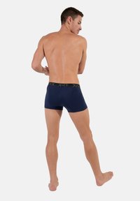 Marinblå boxers i stretchmaterial, med svart elastisk midja med logotyp. Kort benlängd och slät yta.