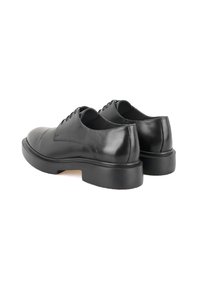 Zwarte leren schoenen met een ronde neus en een dikke zwarte zool. Bevat een gladde textuur en zes oogjes voor veters aan de voorkant.